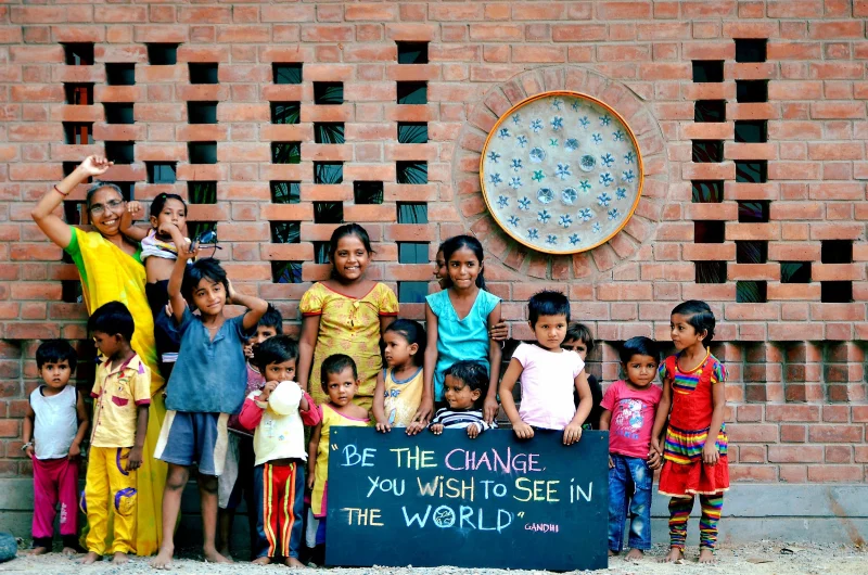 Children outside a preschool built with a patterned brick facade in India